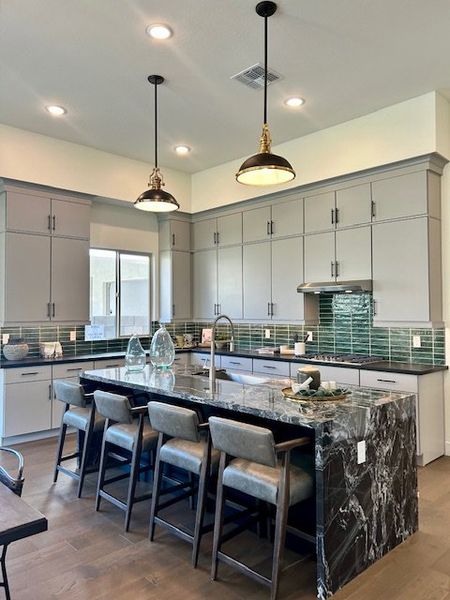 A modern kitchen with sleek cabinetry, marble island, and stylish pendant lighting.