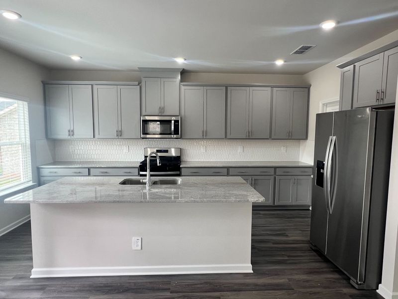 A modern kitchen with sleek gray cabinets, stainless steel appliances, and a large island with marble countertops. A modern kitchen with sleek gray cabinets, stainless steel appliances, and a large island with marble countertops.