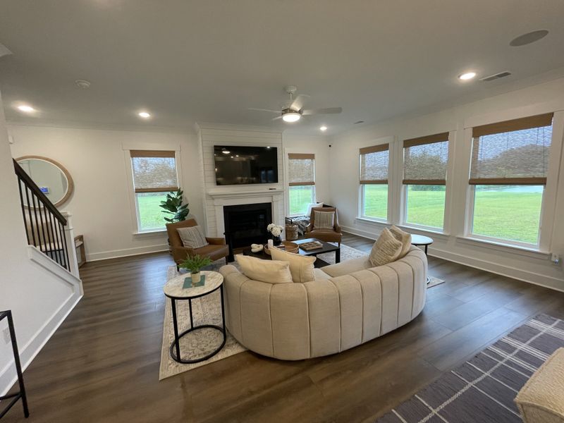A cozy living room with a plush sofa, fireplace, and large windows displaying a serene view, complemented by tasteful decor.