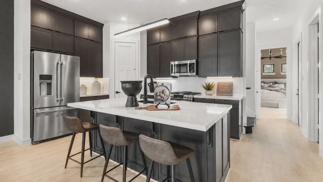 This modern kitchen in Bridgeland Central showcases sleek dark cabinets and white surfaces.