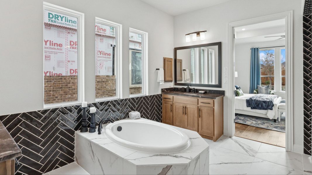 Exquisite marble tub and elegant herringbone tile accent in Green Meadows' luxury home.