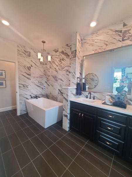 A modern bathroom with marble accents, a sleek bathtub, dark cabinetry, and elegant lighting. A modern bathroom with marble accents, a sleek bathtub, dark cabinetry, and elegant lighting.