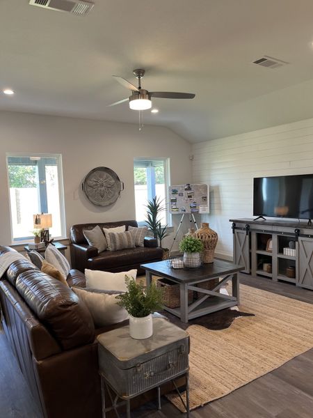 A cozy living room featuring leather sofas, rustic decor, a large TV console, and neutral tones for a welcoming atmosphere.