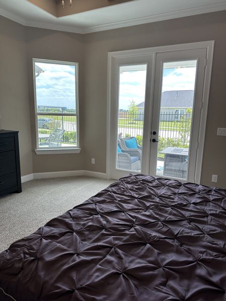 A cozy bedroom with plush carpet, neutral walls, and patio doors offering garden views. A cozy bedroom with plush carpet, neutral walls, and patio doors offering garden views.