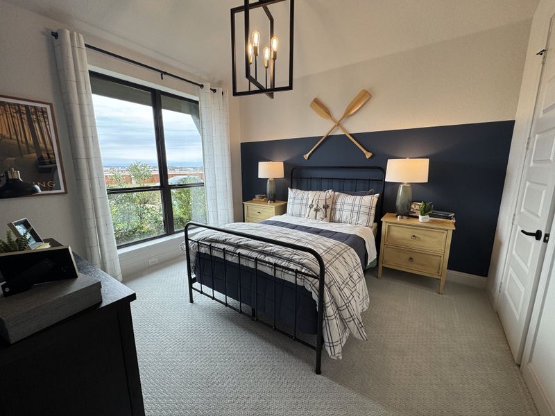Cozy bedroom with plaid bedding, navy accent wall, and large window views, featuring nautical decor and warm wood furniture. Cozy bedroom with plaid bedding, navy accent wall, and large window views, featuring nautical decor and warm wood furniture.