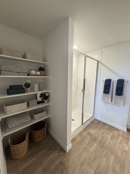 A modern bathroom with a glass shower, open shelving, and stylish wood flooring, offering a clean and organized look. A modern bathroom with a glass shower, open shelving, and stylish wood flooring, offering a clean and organized look.