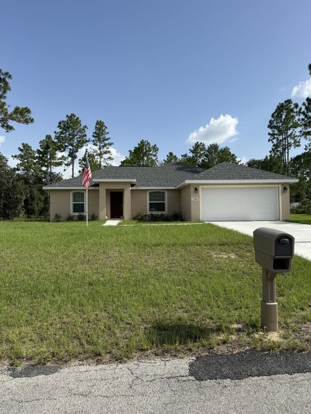 A cozy beige home with a spacious yard and garage in Marion Oaks by Perfect Deed Homes (Ocala, FL).