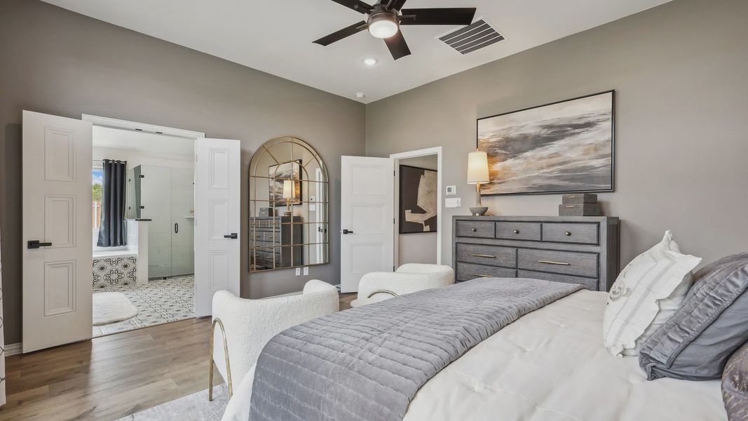 Elegant Churchill bedroom with ensuite bath, featuring a striking mirror, nuanced wood floors, and bespoke artwork. Elegant Churchill bedroom with ensuite bath, featuring a striking mirror, nuanced wood floors, and bespoke artwork.