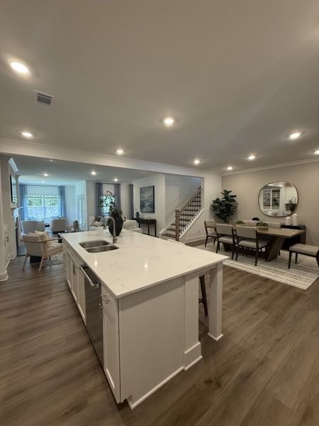 A spacious open-concept kitchen and dining area with a sleek island, warm wood floors, and stylish contemporary decor.