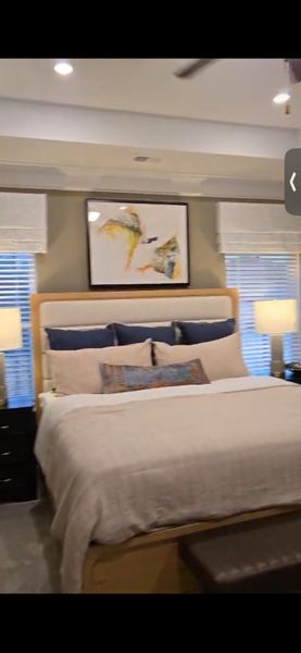 A cozy bedroom featuring a plush bed, elegant lamps, and tasteful abstract art.