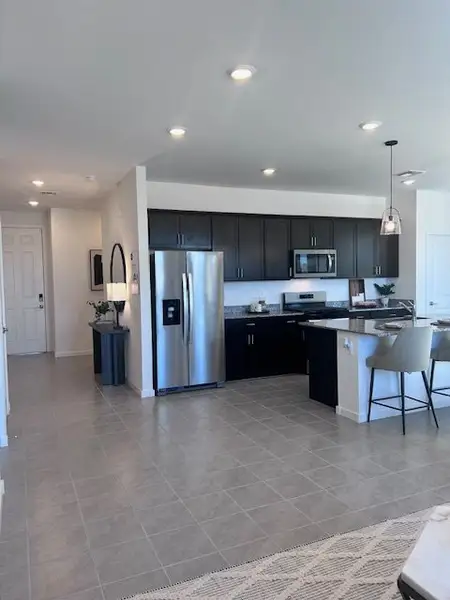 A modern kitchen with dark cabinetry, stainless steel appliances, and a spacious island with seating. A modern kitchen with dark cabinetry, stainless steel appliances, and a spacious island with seating.