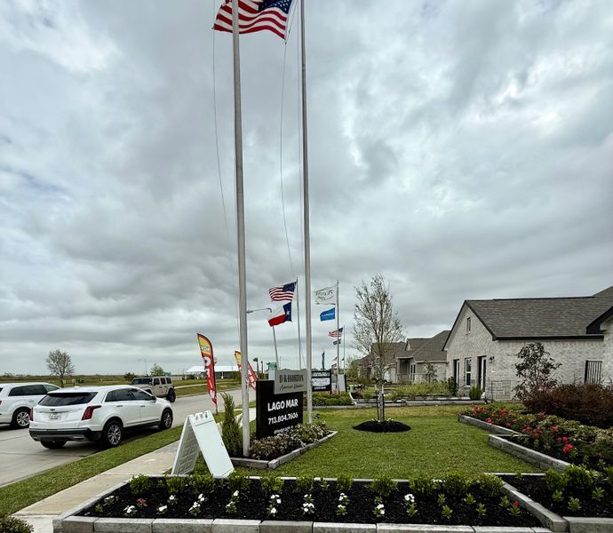 Beautiful homes in Lago Mar by D.R. Horton, Texas City, TX, with well-kept gardens and waving flags lining the street.