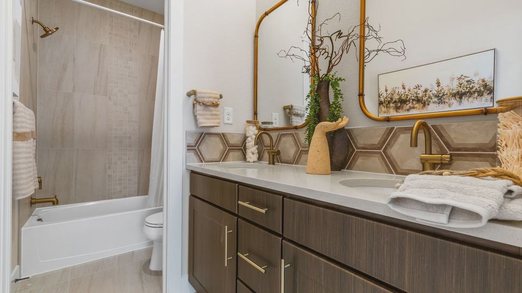 Elegant dual vanity with hexagonal tile backsplash and gold fixtures enhances Dillon Pointe's luxurious charm. Elegant dual vanity with hexagonal tile backsplash and gold fixtures enhances Dillon Pointe's luxurious charm.