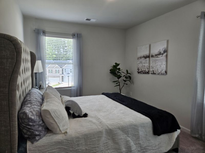 A cozy bedroom featuring a tufted headboard, soft lighting, and decor enhancing a tranquil atmosphere.