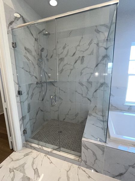 A modern bathroom featuring a striking glass shower with marble-patterned tiles and a hexagonal floor design. A modern bathroom featuring a striking glass shower with marble-patterned tiles and a hexagonal floor design.
