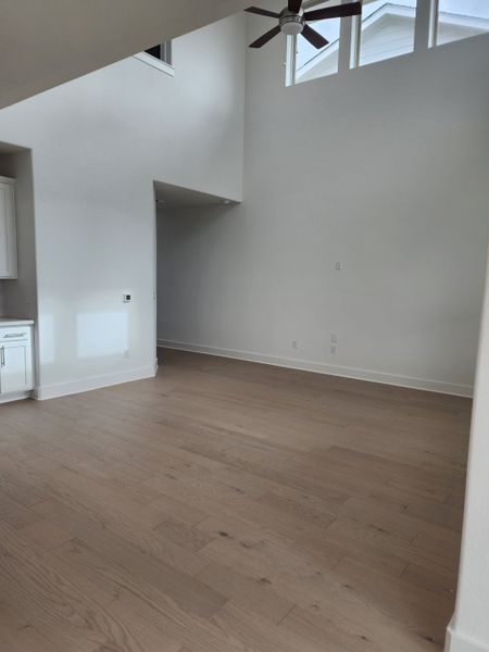 An open, airy living space with high ceilings, wood floors, and natural light from upper windows.
