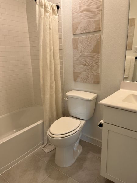 A cozy bathroom with a tiled bathtub, neutral decor, and modern white fixtures.