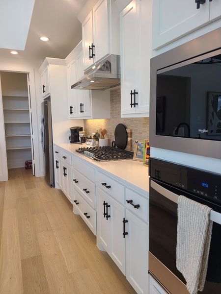 A modern kitchen with white cabinetry, stainless steel appliances, and sleek hardware. A modern kitchen with white cabinetry, stainless steel appliances, and sleek hardware.