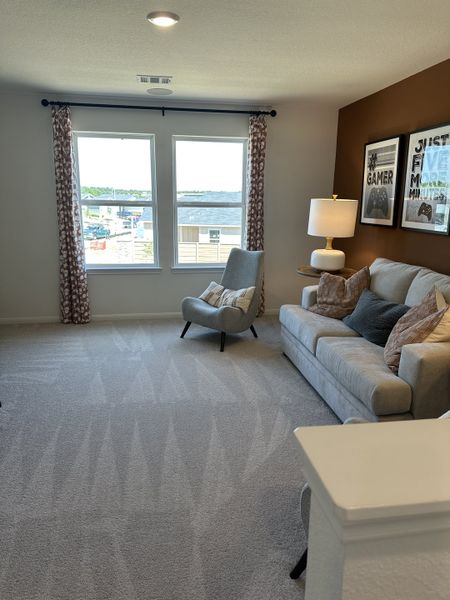 A cozy living area with soft carpeting, a plush sofa, and bright natural light from large windows. A cozy living area with soft carpeting, a plush sofa, and bright natural light from large windows.