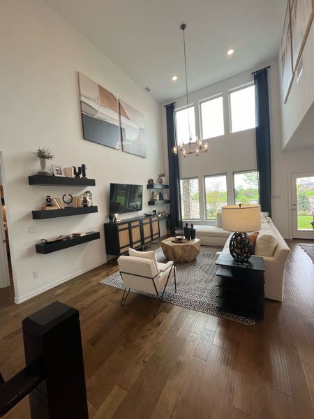 A spacious living room with high ceilings, modern decor, large windows, and a cozy seating area.