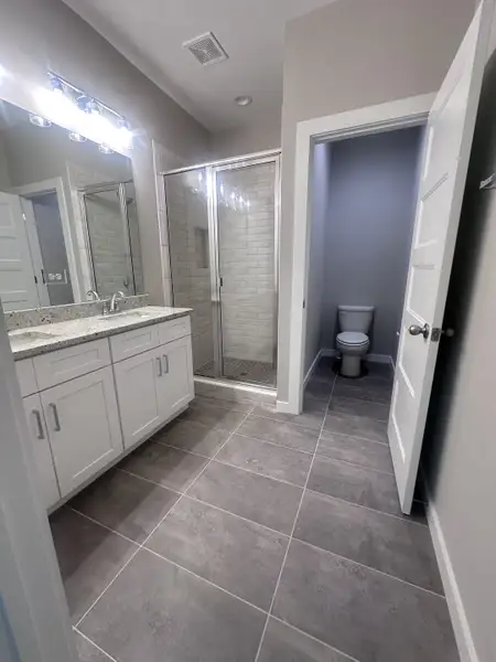 A modern bathroom with a granite countertop, sleek shower, and elegant tile flooring.
