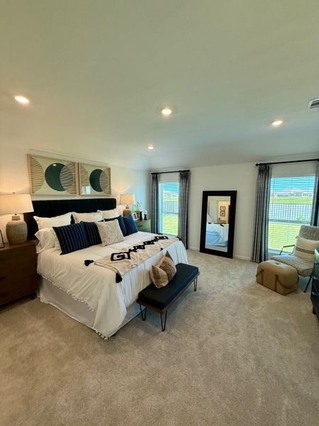 A cozy bedroom with plush carpet, modern decor, a stylish bench, and large windows inviting natural light.