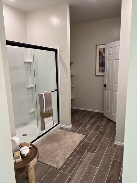 A modern bathroom featuring a spacious shower, wooden tiles, and sleek decor with subtle earth tones.