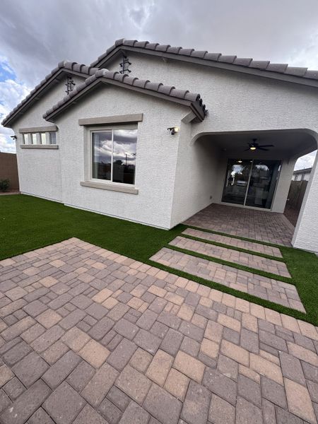 A contemporary white home with a tile roof and patio in Seasons at Trevino by Richmond American Homes (Glendale, AZ).