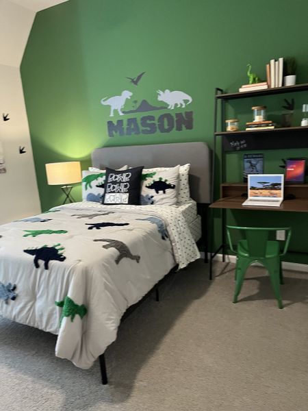 A playful dinosaur-themed bedroom with green accent wall, cozy bedding, and a study nook featuring stylish shelving. A playful dinosaur-themed bedroom with green accent wall, cozy bedding, and a study nook featuring stylish shelving.