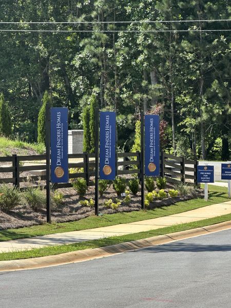 A welcoming entrance with Dream Finders Homes signage in Azalea Hills by Dream Finders Homes, Temple, GA, surrounded by lush greenery.