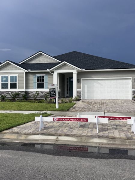 A modern gray home with stone accents and a paved driveway in TrailMark by Richmond American Homes (St. Augustine, FL).