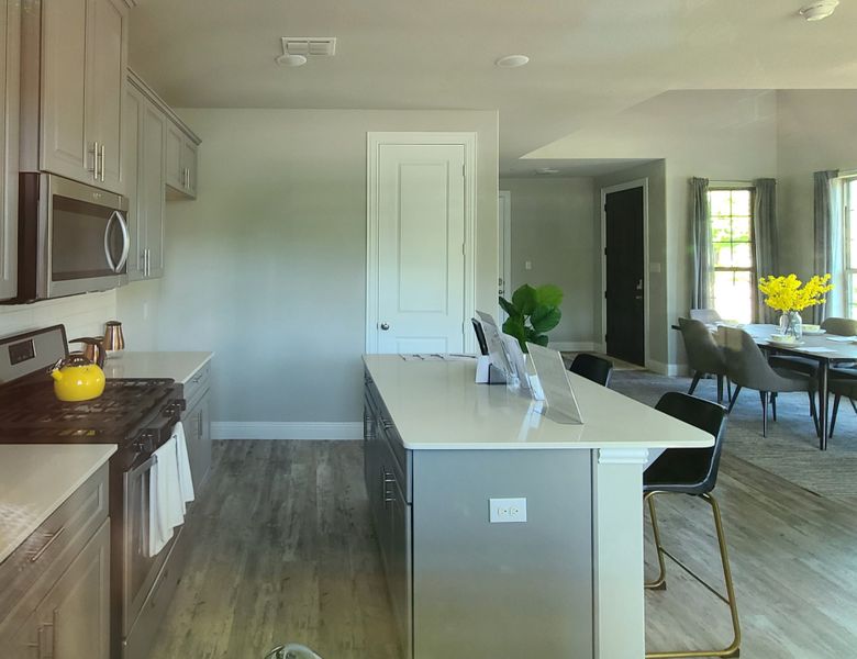 Modern kitchen featuring sleek gray cabinets, a spacious island, and stainless steel appliances with elegant dining space. Modern kitchen featuring sleek gray cabinets, a spacious island, and stainless steel appliances with elegant dining space.