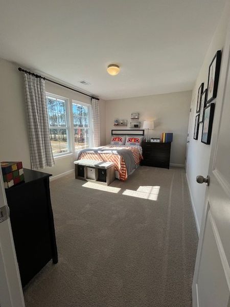 A cozy bedroom featuring a patterned bedspread, large window, and modern decor accents.