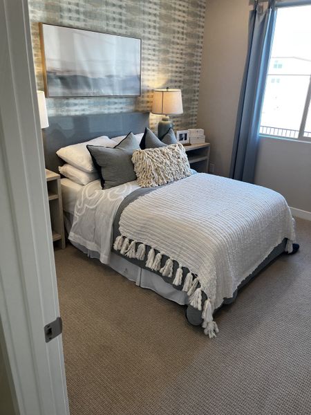 Soft, neutral-toned bedroom with a stylish accent wall, fluffy bedding, and warm lighting for a cozy and inviting feel.