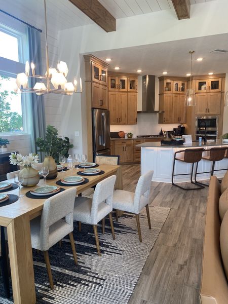 A contemporary kitchen and dining area featuring wooden cabinets, modern lighting, and a stylish dining set.