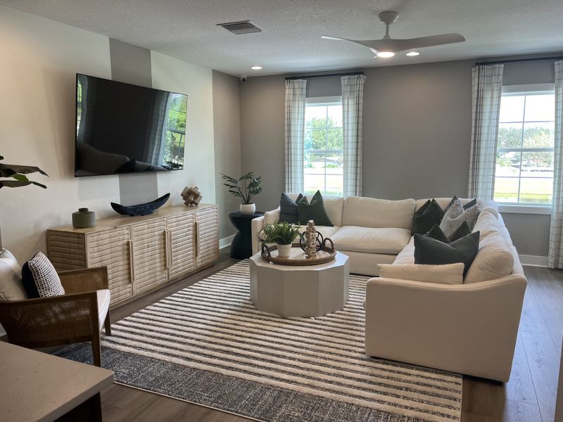 A cozy living room featuring a sleek sectional sofa, stylish accents, and a large wall-mounted TV for modern comfort.