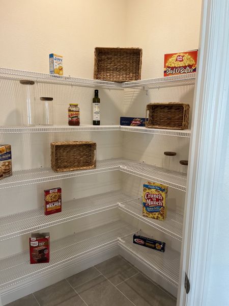 A spacious pantry with organized white wire shelving and a tiled floor, perfect for storage and easy access. A spacious pantry with organized white wire shelving and a tiled floor, perfect for storage and easy access.