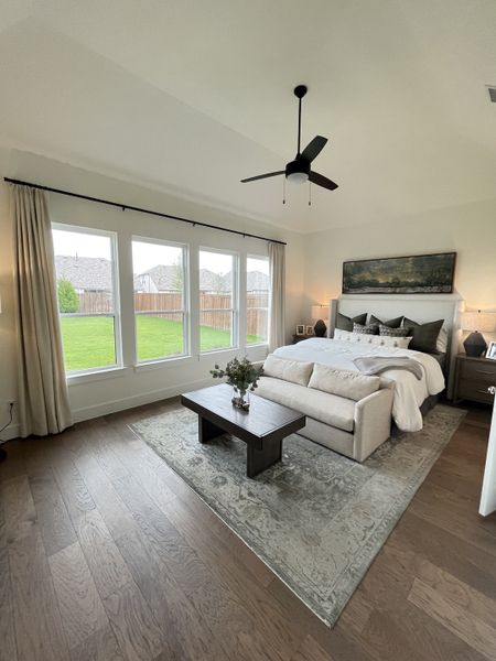 A serene bedroom with a comfy bed, soft rug, large windows, and sleek ceiling fan. A serene bedroom with a comfy bed, soft rug, large windows, and sleek ceiling fan.