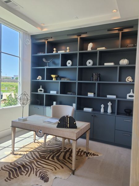 A sophisticated home office featuring built-in dark shelving, a sleek desk, and a zebra-patterned rug.