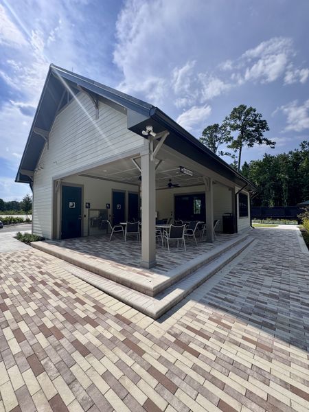 A charming outdoor pavilion with seating on a brick patio in Jennings Farm by Dream Finders Homes (Middleburg, FL).