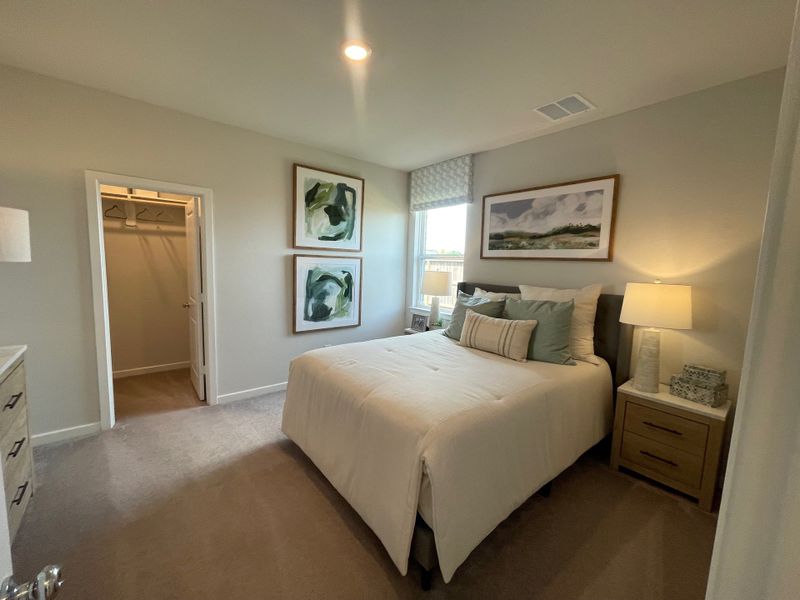 A cozy bedroom features neutral tones, a plush bed, modern art, and soft lighting, offering a peaceful retreat.