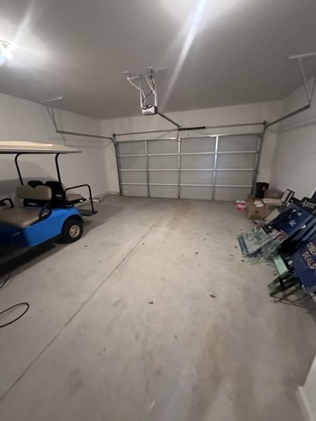 A spacious garage with a clean concrete floor, metal shelves, and a blue golf cart parked inside. A spacious garage with a clean concrete floor, metal shelves, and a blue golf cart parked inside.