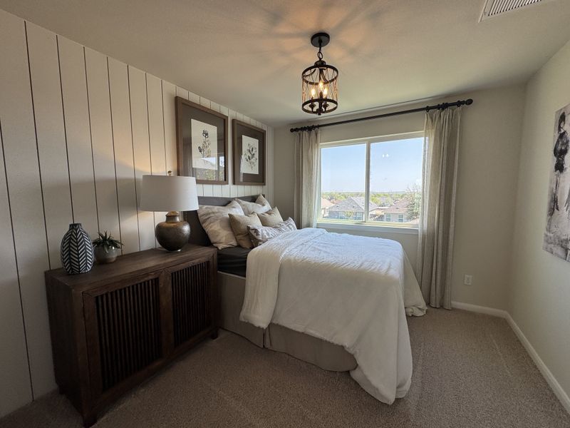 A cozy bedroom with wood accents, a modern light fixture, and large window providing natural light and views. A cozy bedroom with wood accents, a modern light fixture, and large window providing natural light and views.