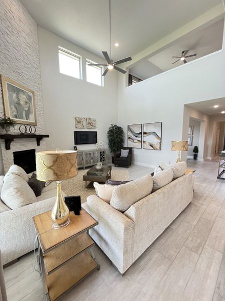 A spacious living room with a high ceiling, modern art, neutral tones, and elegant furnishings.