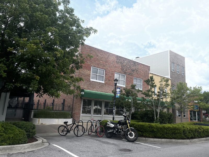 Charming brick storefronts with a green awning and lush greenery in Rivers Edge by DRB Homes (North Charleston, SC).