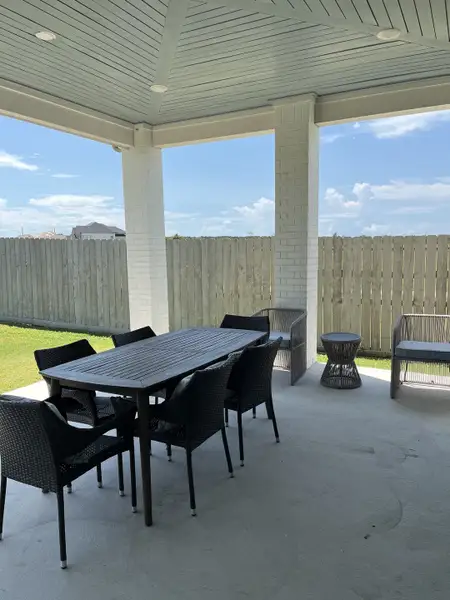 A spacious covered patio with a modern outdoor dining set, perfect for gatherings and relaxation.