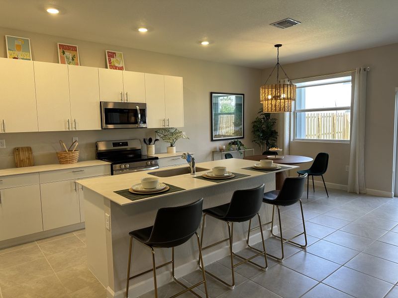 A modern kitchen with sleek white cabinets, a central island, and chic lighting, creating a warm and inviting atmosphere.