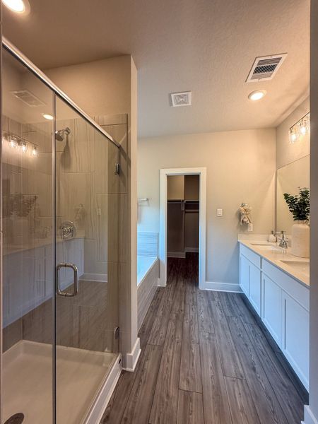 A modern bathroom featuring a glass shower, dual vanity, and elegant wood flooring for a refined touch.