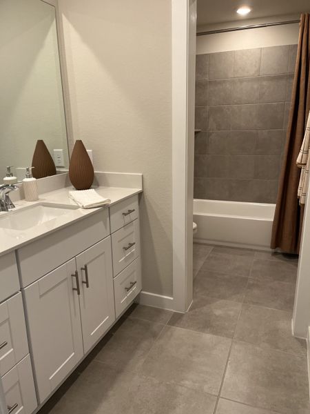 A modern bathroom with a sleek white vanity, elegant fixtures, and gray tiled flooring for a contemporary touch.