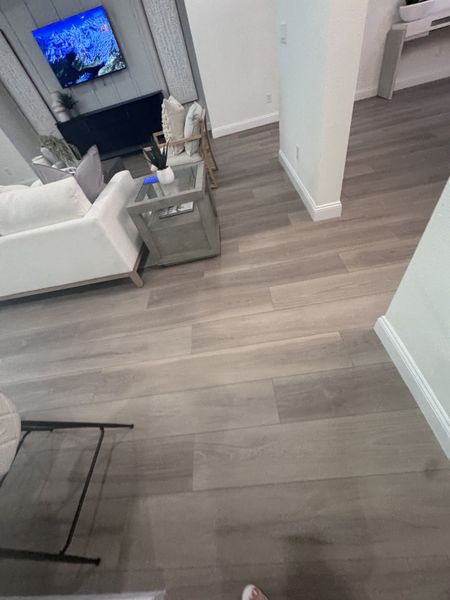 A cozy living space with wood flooring, white sofa, and mounted TV, creating a modern and inviting atmosphere.